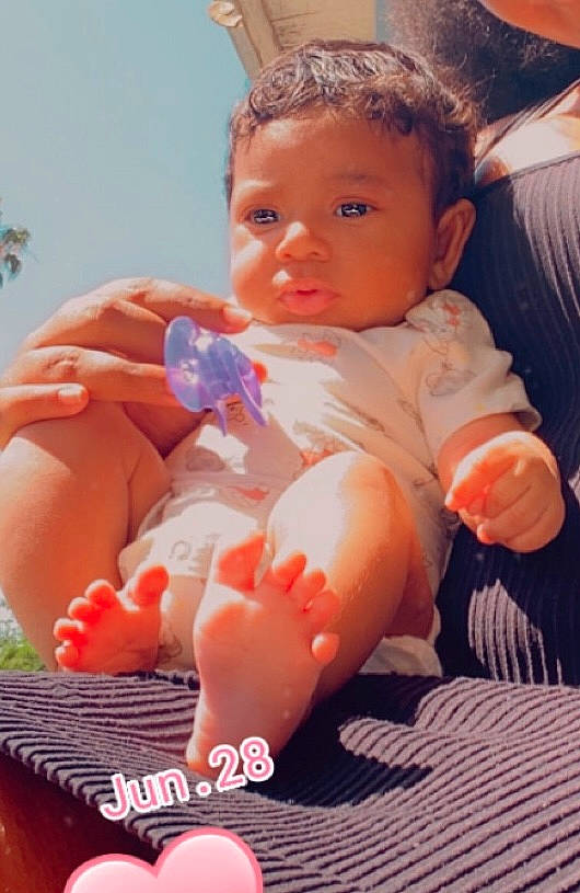 Jahnay is registered to the contest to win money with this photo: baby, baby_products, baby_toddler_clothing, cheek, child, comfort, dress, finger, hand, head, human_body, human_leg, leg, nail, orange, person, pink, sitting, skin, thumb