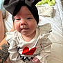 Hadley joined the competition — help win amazing prizes! baby, infant, headband, bow, white_clothing, red_heart, tattoo, bed, blanket, person, cute, indoors, skin, hand, face, eyes, tongue, sitting, clothing, soft_light
