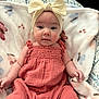 baby, infant, child, headband, bow, coral_outfit, blanket, butterfly_pattern, soft_texture, indoor, portrait, cute, smiling, hands, face, eyes, seated, cozy, apparel, closeup