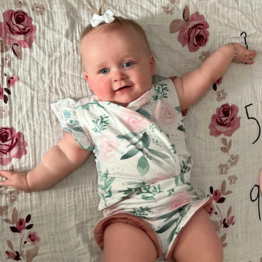 Aspen is registered to the contest to win money with this photo: baby, bodypart, clothing, dress, face, finger, flower, footwear, furniture, hand, head, newborn, person, photography, plant, portrait, sandal, shoe, shorts, sitting