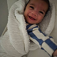 Dontae is registered to the contest to win money with this photo: baby, smiling, blanket, knitted, cozy, child, infant, reaching, striped_clothing, blue, white, happy, portrait, cute, warm, soft_lighting, closeup, wrapped, indoor, person