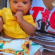Kaliani joined the competition — help win amazing prizes! baby, child, infant, headband, yellow_clothing, sunflower_skirt, barefoot, hand, face, eyes, adult, necklace, sitting, curious, outdoor, person, fashion, cute, portrait, holding