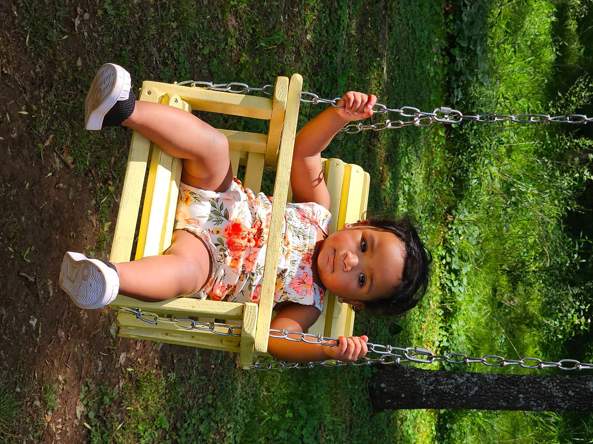 Nevaeh Mae is registered to the contest to win money with this photo: baby, baby_toddler_clothing, child, city, fence, fun, grass, happy, leisure, outdoor_play_equipment, people_in_nature, person, plant, recreation, sandal, sitting, smile, sneakers, swing, toddler