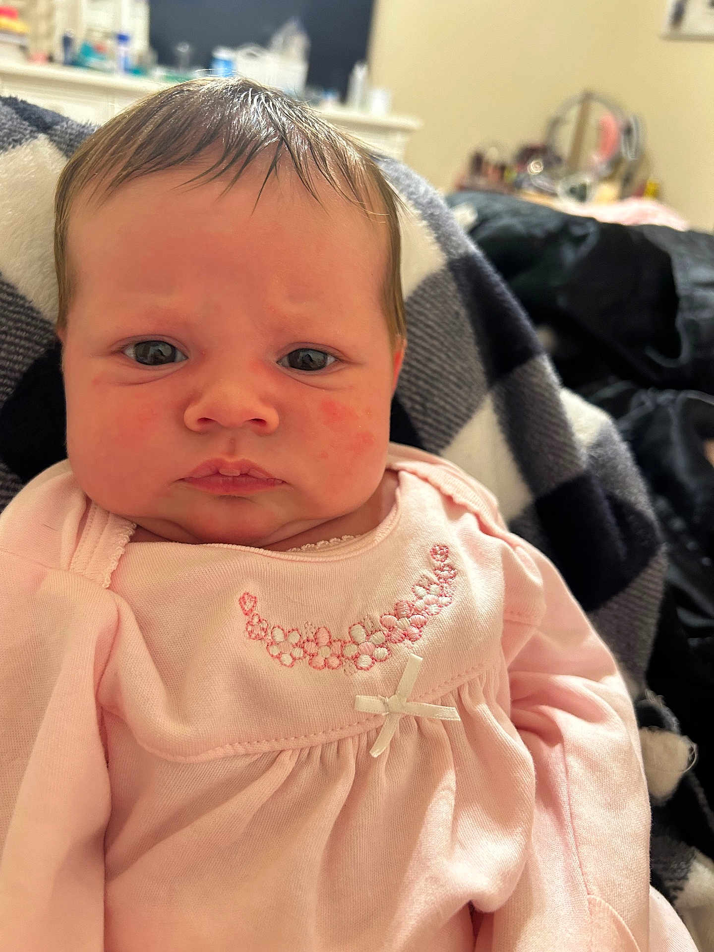 Ainsley is registered to the contest to win money with this photo: baby, infant, face, pink_clothing, blanket, embroidered, portrait, indoor, closeup, child, serious_expression, newborn, soft_lighting, person, cute, young_child, sitting, warm, cozy, fabric