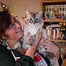 Bonbon a rejoint le concours — aidez-le/la à gagner de superbes lots ! woman, cat, indoor, glasses, smile, fluffy_cat, blue_eyes, holding, bookshelf, books, earrings, portrait, home, person, furniture, decor, face, hands, apron, cozy
