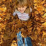 Lillian is registered to the contest to win money with this photo: child, autumn_leaves, fall, playful, smiling, outdoor, nature, jeans, striped_shirt, blond_hair, sunlight, leaf_pile, happy, casual_clothing, young_child, seasonal, grass, fun, portrait, park