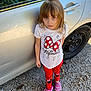 child, car, gravel, outdoor, white_shirt, red_leggings, pink_slippers, minnie_mouse, expression, standing, person, clothing, footwear, vehicle, toddler, hair, casual, daylight, side_view, young