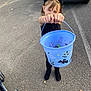 child, girl, halloween, costume, cat_ears, bucket, candy, black_clothing, boots, asphalt, parking_lot, car, toy_stroller, outdoor, smiling, holding, trick_or_treat, daylight, holiday, celebration
