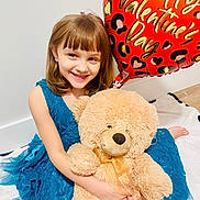 Lillian joined the competition — help win amazing prizes! balloon, bangs, bare_foot, child, floor, girl, happy, heart_balloon, hugging, indoor, playful, portrait, sitting, smile, stuffed_animal, teal_dress, teddy_bear, valentine_balloon, white_wall, young_child
