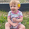 Nova is registered to the contest to win money with this photo: baby, child, cute, daylight, earring, fence, flower, grass, greenery, happy, nature, onesie, outdoor, person, playful, sitting, skin, smiling, yellow_flower, young_child
