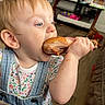 Nova is registered to the contest to win money with this photo: baby, blue_eyes, chicken, child, cute, denim_overalls, drumstick, earring, eating, floor, floral_shirt, food, furniture, hand, indoor, living_room, meal, person, toddler, toy