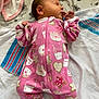 newborn, baby, sleeping, pink_onesie, milk_bottle_pattern, cookie_pattern, star_pattern, bed, blanket, soft_texture, infant, child, cute, cozy, lying_down, peaceful, indoors, fabric, clothing, portrait