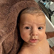Daniel is registered to the contest to win money with this photo: baby, infant, wet_skin, towel, bath, face, eyes, mouth, skin, head, curious, expression, closeup, child, water_droplets, indoors, human, person, portrait, newborn