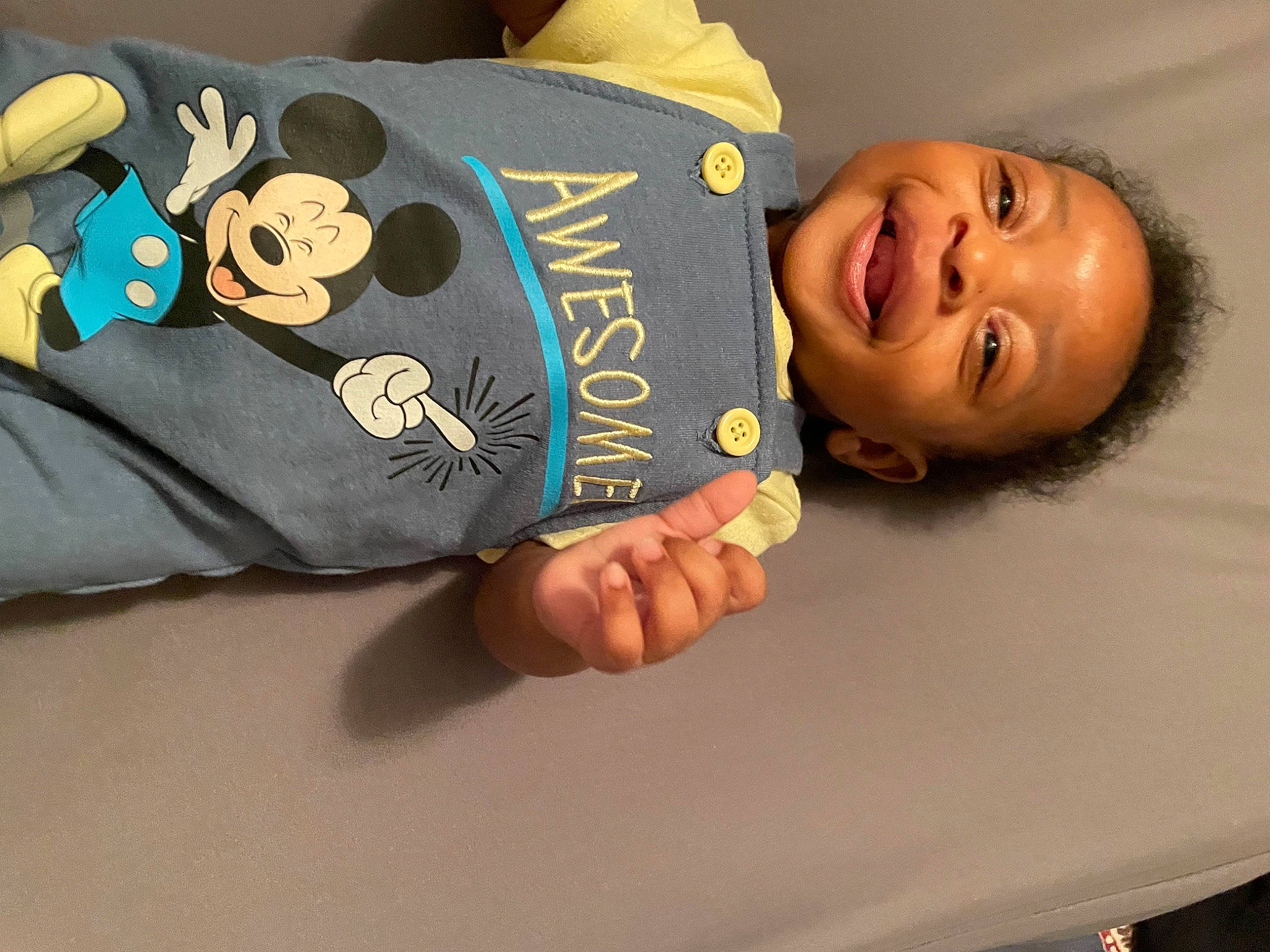 Bruce is registered to the contest to win money with this photo: baby, baby_toddler_clothing, bag, book, child, comfort, facial_expression, fashion_accessory, finger, font, fun, hand, happy, head, linens, person, room, sleeve, smile, t_shirt