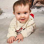 Lily joined the competition — help win amazing prizes! baby, child, smiling, face, hands, sweater, polka_dots, lying_down, indoors, holiday, decorations, warm_lighting, cute, portrait, infant, cheerful, young, cozy, background, happy