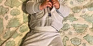 Soujah-Flint is registered to the contest to win money with this photo: baby, infant, pacifier, blanket, dinosaur_pattern, clothing, hat, lying_down, indoor, cute, child, toddler, soft_texture, portrait, hands, face, cozy, warm, casual, resting