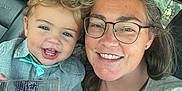 Thomas is registered to the contest to win money with this photo: toddler, child, woman, glasses, smile, car_interior, seat, window, sunlight, clothing, hair, blue_eyes, plastic_cup, happy, portrait, casual, family, closeup, person, indoor
