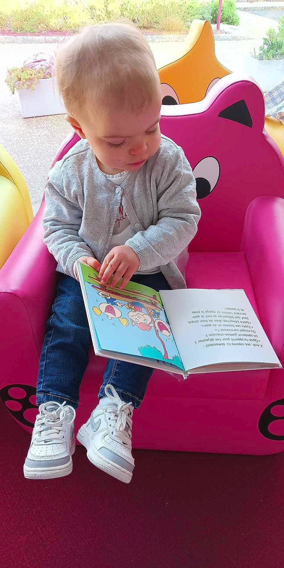Emmy a rejoint le concours — aidez-le/la à gagner de superbes lots ! baby, baby_playing_with_toys, baby_toddler_clothing, book, carmine, child, flooring, fun, grass, lap, leisure, magenta, person, pink, play, product, reading, sitting, snapshot, sock