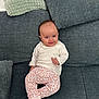 baby, child, comfortable, couch, cozy, cushion, cute, furniture, gray_couch, happy, home, indoor, infant, patterned_pants, pink_sock, portrait, sitting, smiling, white_top, young_child