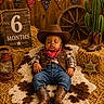 Makari is registered to the contest to win money with this photo: baby, infant, sleeping, cowboy, hat, bandana, boots, plaid_shirt, vest, jeans, portrait, milestone, six_months, rustic, western, hay, cactus, lantern, wagon_wheel, studio_photography