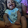 Makari is registered to the contest to win money with this photo: baby, child, infant, smiling, laughing, portrait, indoor, couch, cushion, seated, onesie, clothing, family, hands, legs, patterned_fabric, home, happy, closeup, casual_photo