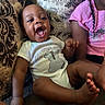 baby, infant, child, toddler, smiling, laughing, portrait, sitting, couch, sofa, cushion, indoors, home, pink_shirt, braids, onesie, barefoot, family, happy, closeup