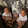 children, siblings, baby, toddler, infant, couch, cushions, sitting, portrait, indoor, matching_outfits, racing_car, clothing, smiling, looking_at_camera, hand_gesture, family, home, photography, safe