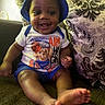 baby, child, smiling, sitting, portrait, indoor, couch, cushion, blue_hat, tshirt, shorts, teddy_bear, basketball, barefoot, feet, happy, infant, living_room, patterned_fabric, photography