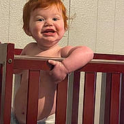 Georgia is registered to the contest to win money with this photo: toddler, child, crib, red_hair, diaper, smile, indoor, wooden_crib, baby, happy, grip, face, arm, skin, wall, furniture, playful, cute, person, infant