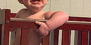 Georgia is registered to the contest to win money with this photo: arm, baby, child, crib, cute, diaper, face, furniture, grip, happy, indoor, infant, person, playful, red_hair, skin, smile, toddler, wall, wooden_crib