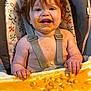 Georgia is registered to the contest to win money with this photo: baby_food, child, clothing_straps, cute, face, feeding_time, food, fun, hands, happy, high_chair, indoor, meal, messy, orange, person, red_hair, smiling, toddler, tray