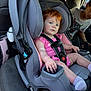 toddler, child, car_seat, car_interior, seatbelt, pink_clothing, gray_car_seat, red_hair, blue_eyes, socks, person, vehicle, seat, safety_harness, baby, young_child, star_wars_tshirt, window, daylight, family
