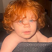 Georgia is registered to the contest to win money with this photo: baby, baby_toddler, bare_shoulders, blue_eyes, child, closeup, curious, curly_hair, cute, expression, face, hair, indoor, infant, mesh_barrier, person, portrait, red_hair, skin, young_child