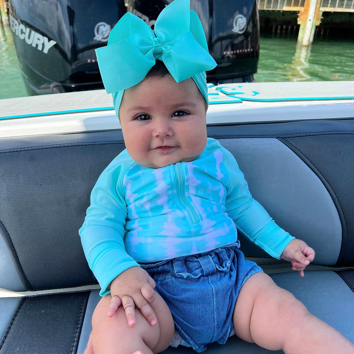 Aitana is registered to the contest to win money with this photo: baby, bodypart, cap, clothing, face, finger, hand, hat, head, helmet, pants, people, person, photography, portrait, shorts, sitting, swimwear, water, waterfront