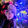 toddler, child, winter_clothing, hat, ear_flaps, red_and_black_checkered, face, curious, snow, holiday_lights, colorful_lights, night, outdoor, winter, cold_weather, portrait, close_up, young_child, cute, warm_clothing