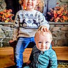 child, children, baby, toddler, indoor, sweater, jeans, onesie, fireplace, flowers, carpet, wood_floor, smiling, curly_hair, blond_hair, cute, family, portrait, sibling, home