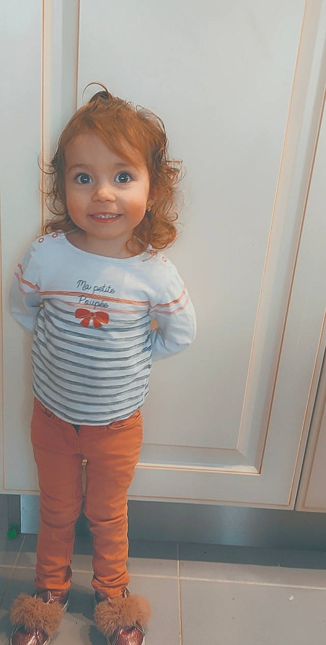 Mélina participe au concours pour gagner de l'argent avec cette photo : baby_toddler_clothing, cheek, denim, elbow, electric_blue, face, flooring, hairstyle, happy, human_body, joy, knee, pattern, person, room, sleeve, smile, standing, t_shirt, toddler