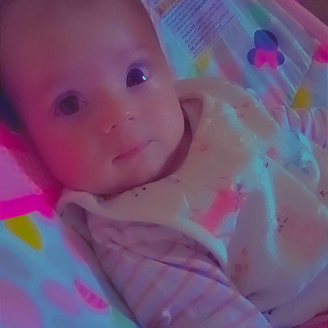 Mya participe au concours pour gagner de l'argent avec cette photo : baby, baby_bouncer, child, closeup, clothing, colorful, cute, expression, face, indoor, infant, lying_down, patterned, person, portrait, resting, seat, soft_lighting, striped, young