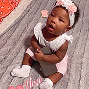 Nykajiah is registered to the contest to win money with this photo: baby, infant, child, sitting, blanket, headband, flower, phone, drool, pink_shorts, white_shirt, socks, pillow, orange_bandana, bed, indoor, cute, curious_expression, home, soft_texture
