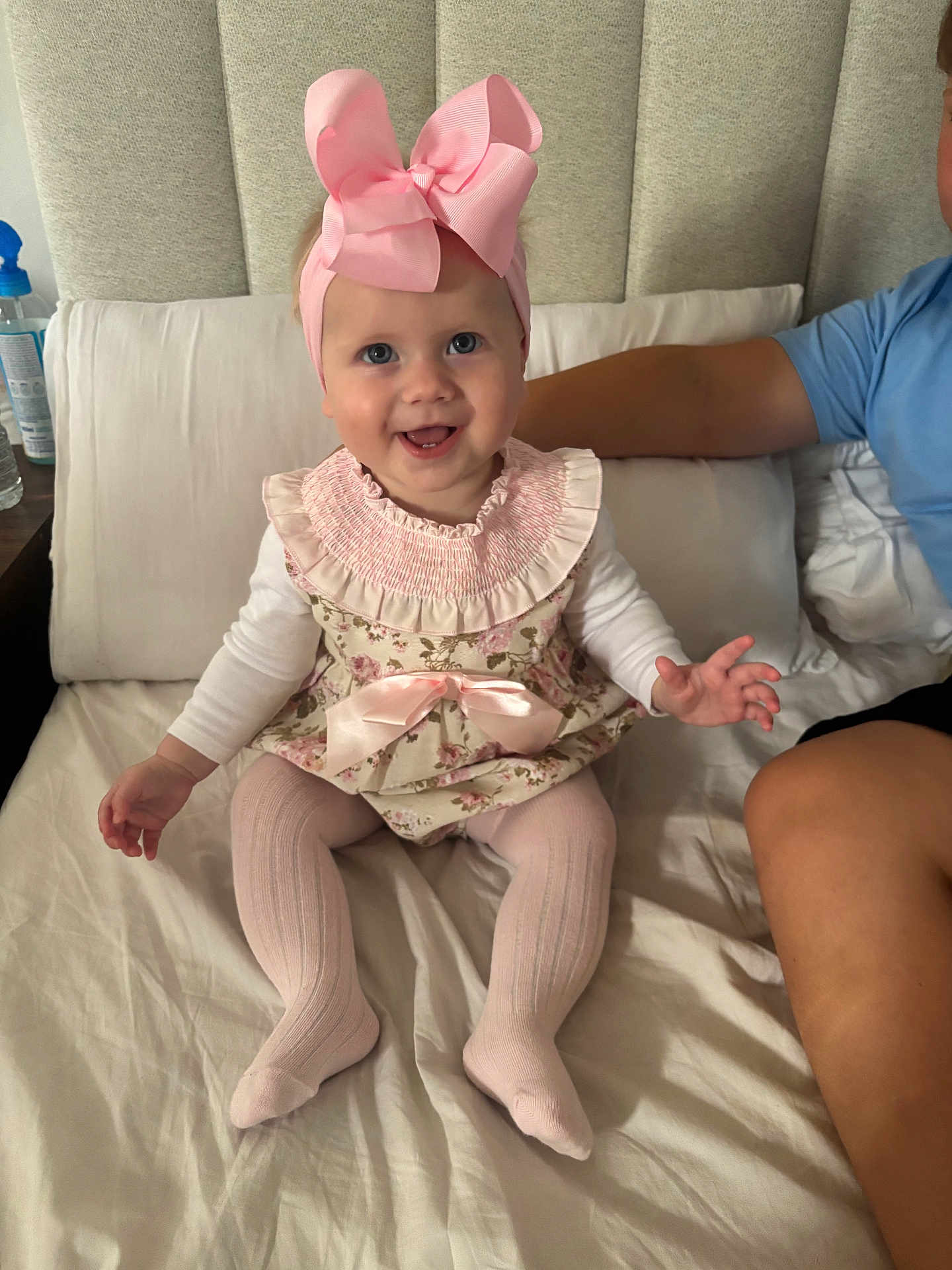 Darla-Marie joined the competition — help win amazing prizes! baby, child, pink_bow, headband, floral_dress, tights, bed, pillow, smile, happy, arm, person, indoors, fabric, cushion, cute, infant, sitting, human, portrait
