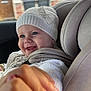 Darla-Marie is registered to the contest to win money with this photo: baby, child, car_seat, smile, hat, knitwear, hand, holding, window, car, seatbelt, face, blue_eyes, clothing, indoor, person, cute, happy, infant, warm