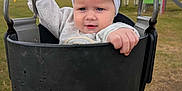 Darla-Marie is registered to the contest to win money with this photo: baby, child, swing, playground, outdoor, grass, bow, headband, white_clothing, toddler, seat, metal, sky, cloudy, hand, legs, rope, park, fun, cute