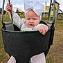 baby, child, swing, playground, outdoor, grass, bow, headband, white_clothing, toddler, seat, metal, sky, cloudy, hand, legs, rope, park, fun, cute
