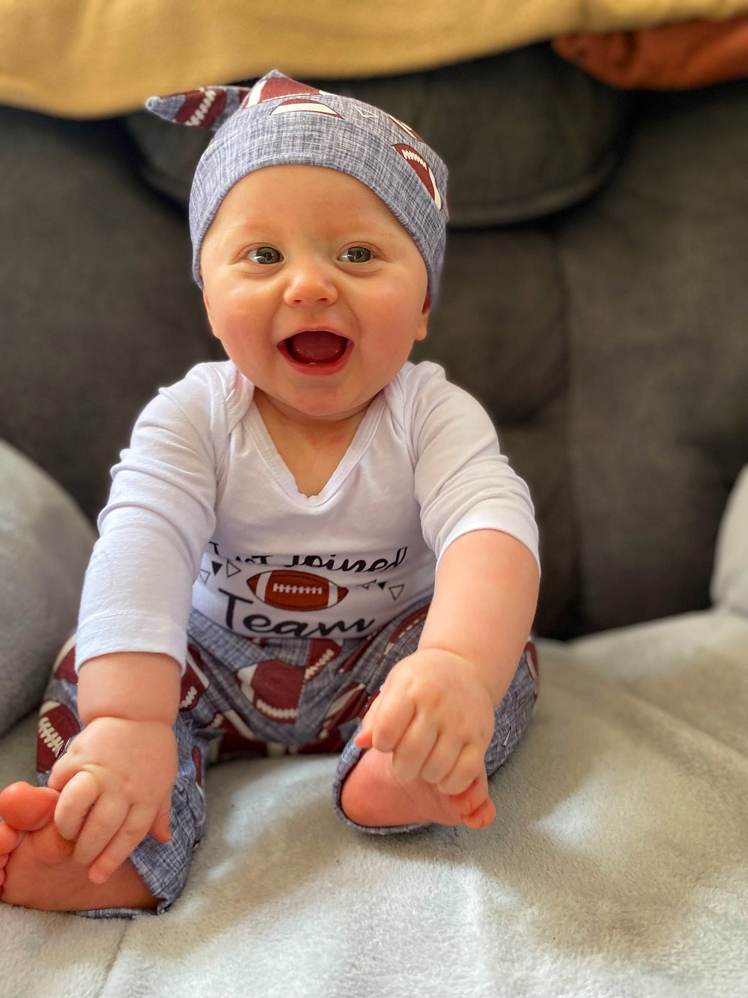 Zaylin is registered to the contest to win money with this photo: arm, baby, baby_toddler_clothing, cap, cheek, child, chin, comfort, finger, flooring, fun, happy, headgear, headwear, person, sitting, skin, sleeve, smile, t_shirt