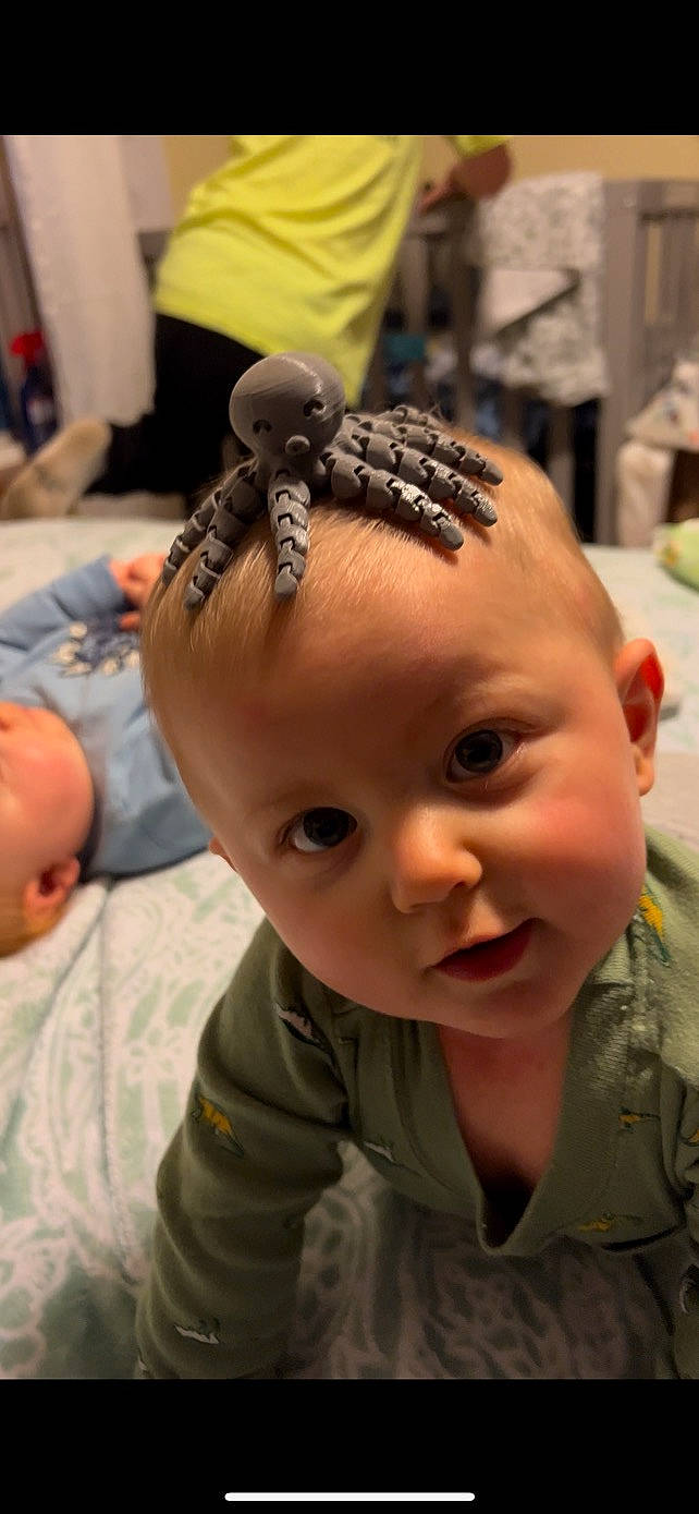 Zaylin is registered to the contest to win money with this photo: audio_equipment, baby, baby_toddler_clothing, cheek, child, ear, eyebrow, eyelash, forehead, fun, hair_accessory, happy, headpiece, military_camouflage, mouth, nose, person, sitting, skin, toddler