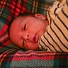 newborn, baby, infant, sleeping, face, portrait, blanket, striped_blanket, cozy, indoors, close_up, resting, lying_down, warm_lighting, red, gray, textile, candid, child, soft_focus