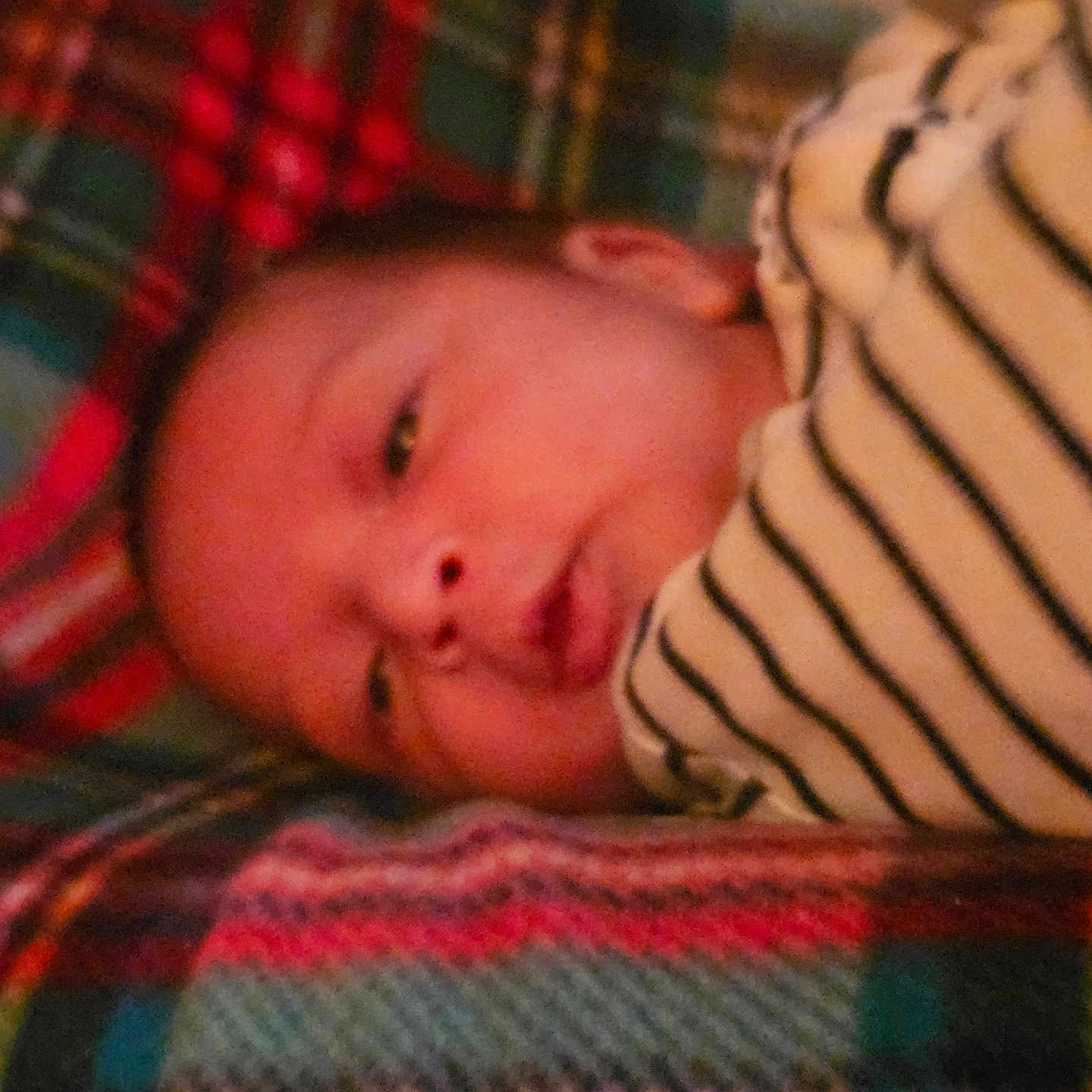 Jacob is registered to the contest to win money with this photo: newborn, baby, infant, sleeping, face, portrait, blanket, striped_blanket, cozy, indoors, close_up, resting, lying_down, warm_lighting, red, gray, textile, candid, child, soft_focus