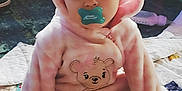 Ava joined the competition — help win amazing prizes! baby, child, pacifier, pink_clothing, onesie, headband, bow, bear_design, quilt, sitting, indoor, soft_light, cute, portrait, infant, face, eyes, cozy, plush, floor