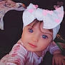 Ava is registered to the contest to win money with this photo: child, baby, headband, bow, pink_hearts, closeup, portrait, indoor, cute, expression, face, hand, long_sleeve, patterned_clothing, soft_lighting, selfie_pose, young_child, looking_at_camera, floral_pattern, cozy