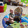 Asher joined the competition — help win amazing prizes! baby, child, indoor, toy, playroom, colorful, wooden_toy, activity_center, rug, floor, furniture, chair, childrens_toy, play, kneeling, smiling, happy, person, young_child, casual_clothing